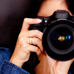 Portrait of a photographer covering her face with the camera