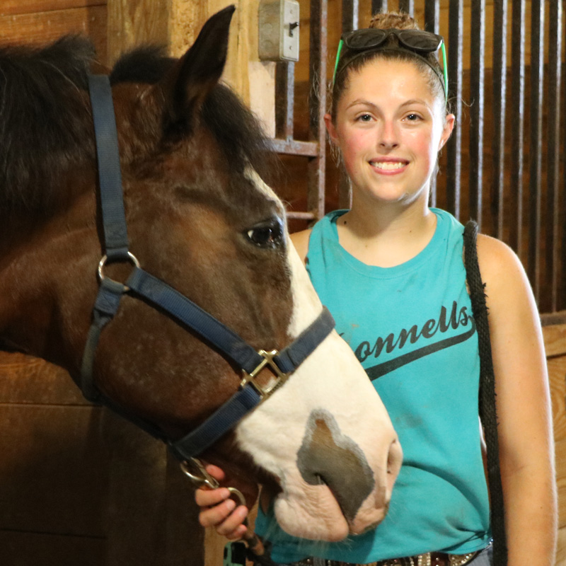 Student standing next to a horse