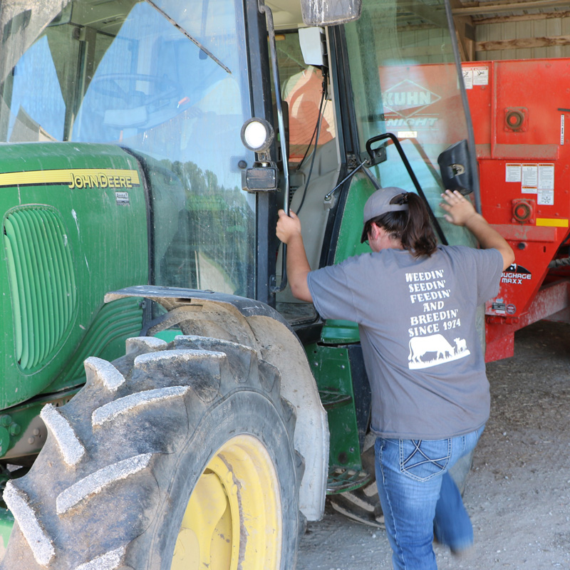 student climbing in to a John Deere tractor