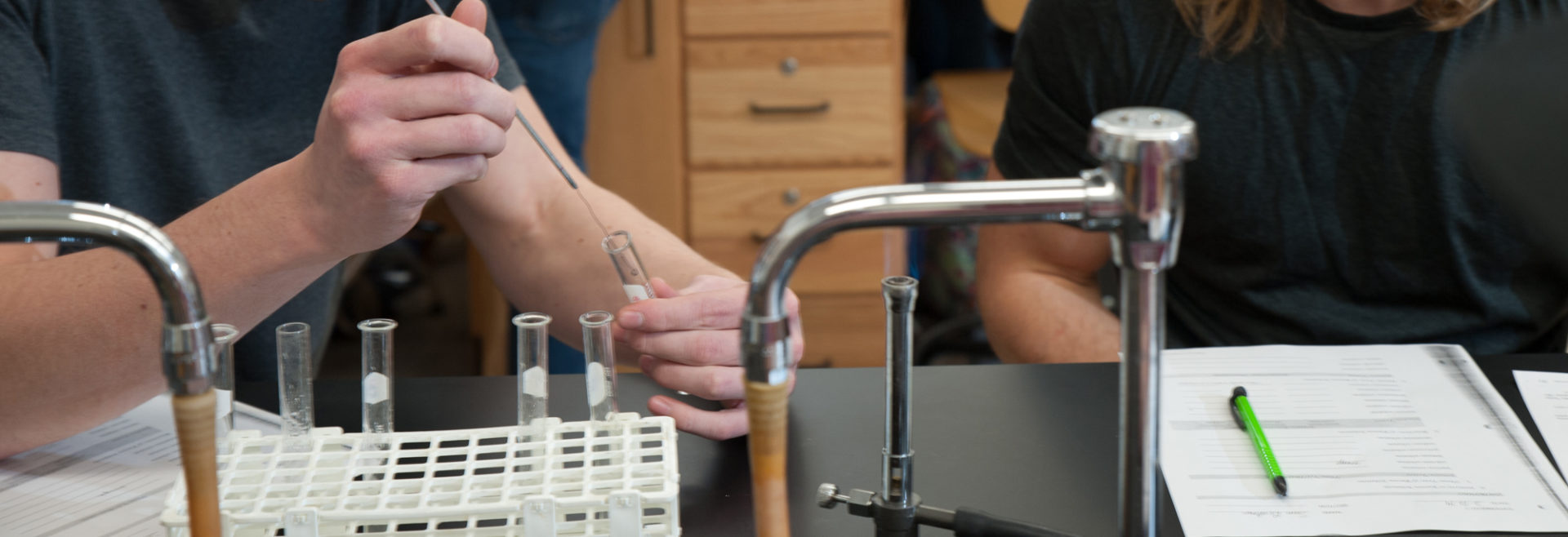 student holding glass test tube in class