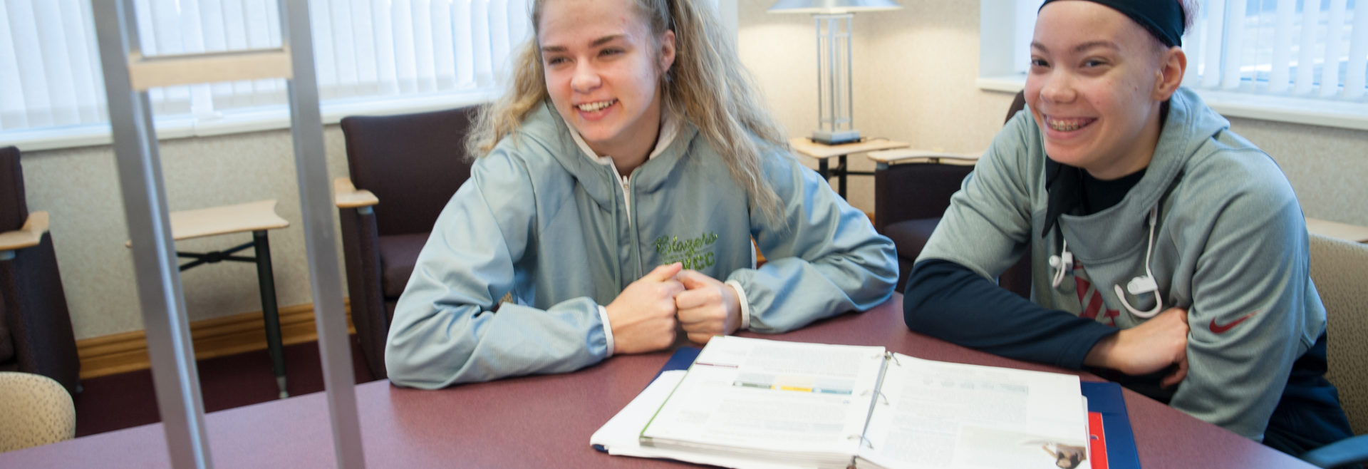 two students at a table with a binder in front of then