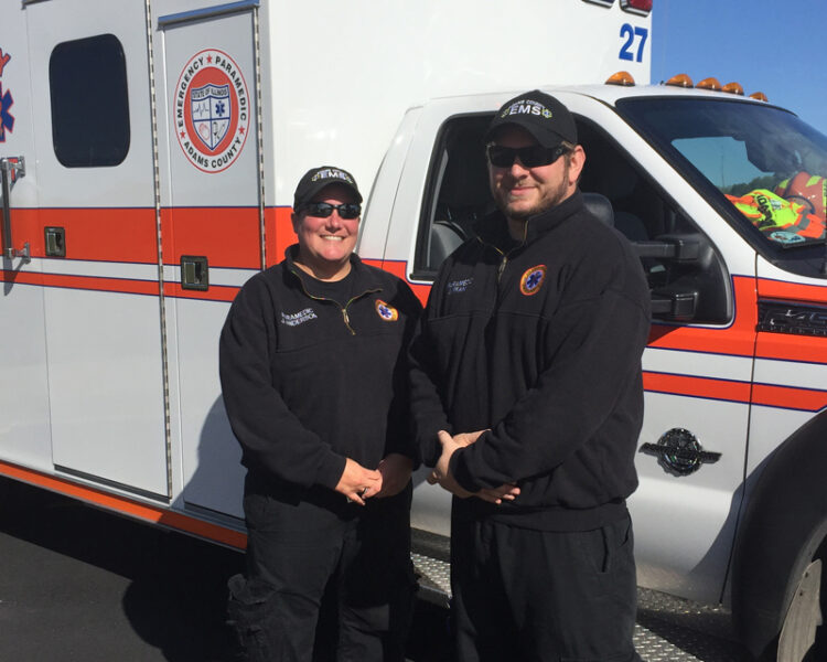 two paramedics standing next to the ambulance