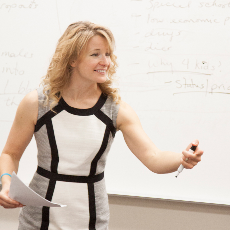 female instructor with papers in one hand and marker in other