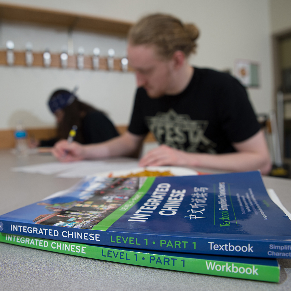 two college books on desk in front of student