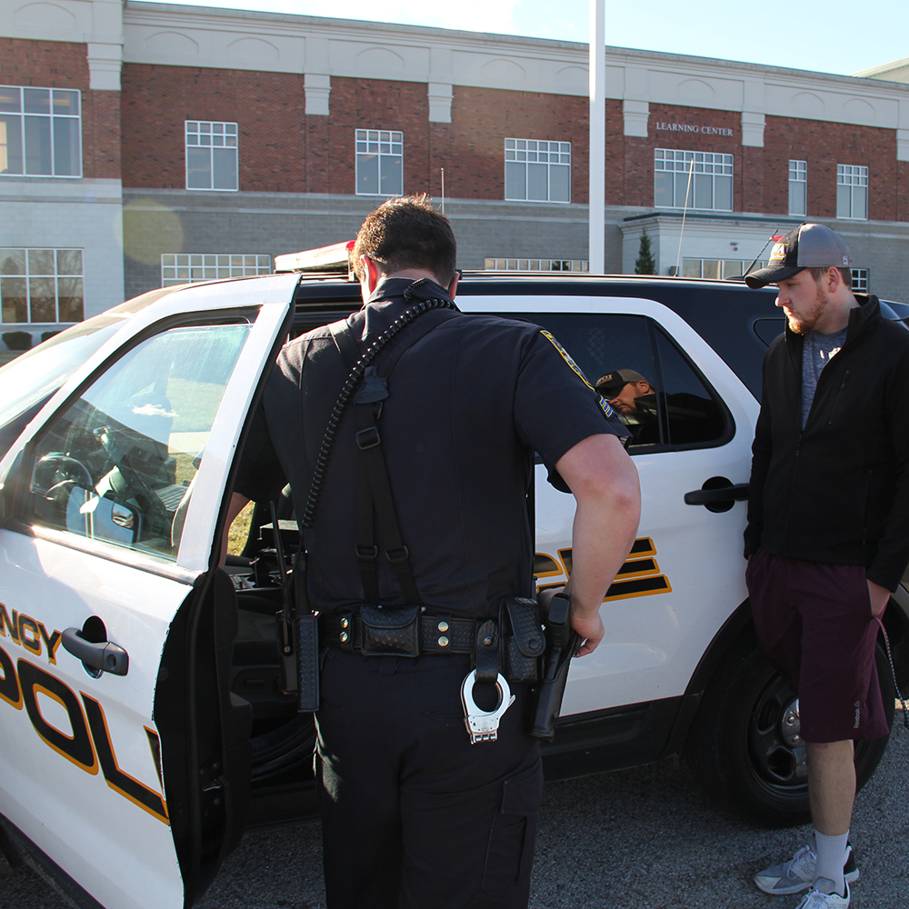 police officer and student next to officers car