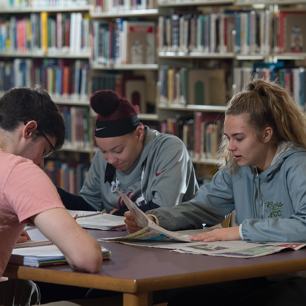 three students at a table reading