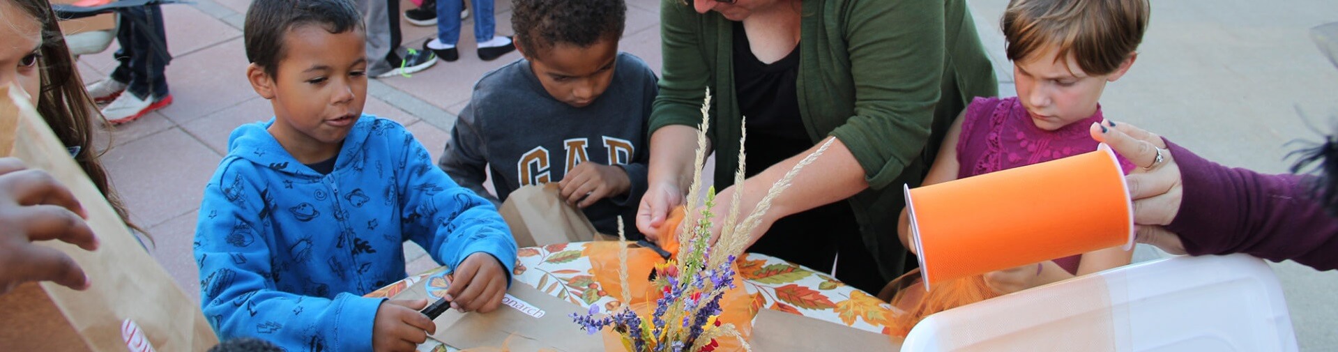 Children gather to make crafts at the directions of their teacher