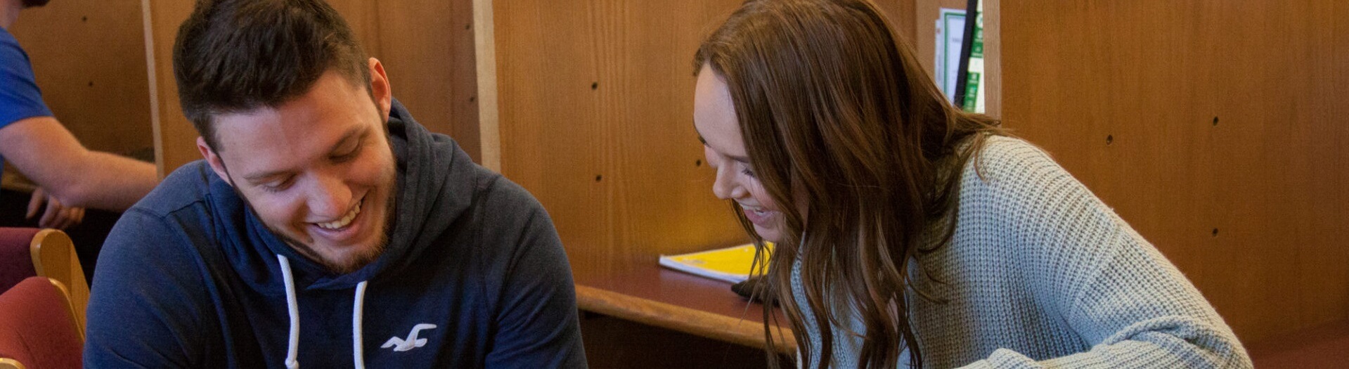 Two students chuckle as they study in the John Wood Community College library