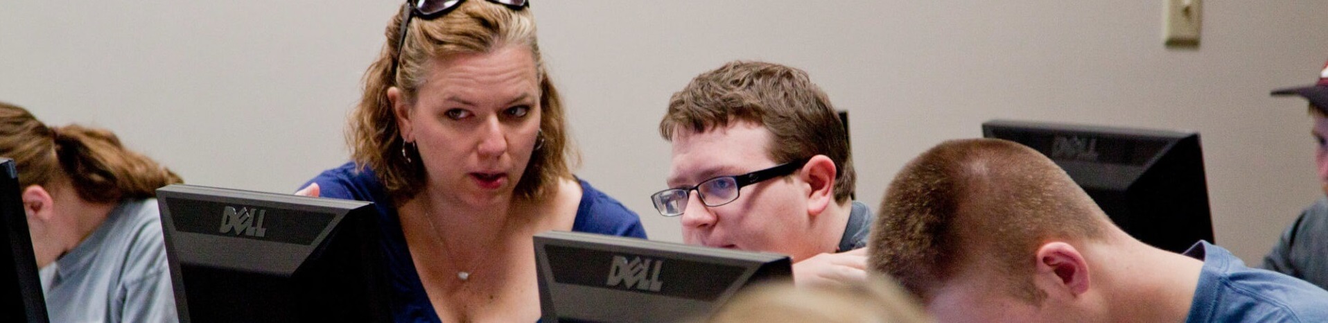 Professor explains concept to student working at computer