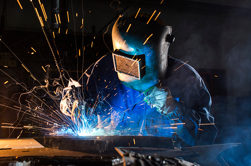 Welder wears heavy gear as they craft their material