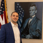 Artist Nevin McNally Stands next to his painting