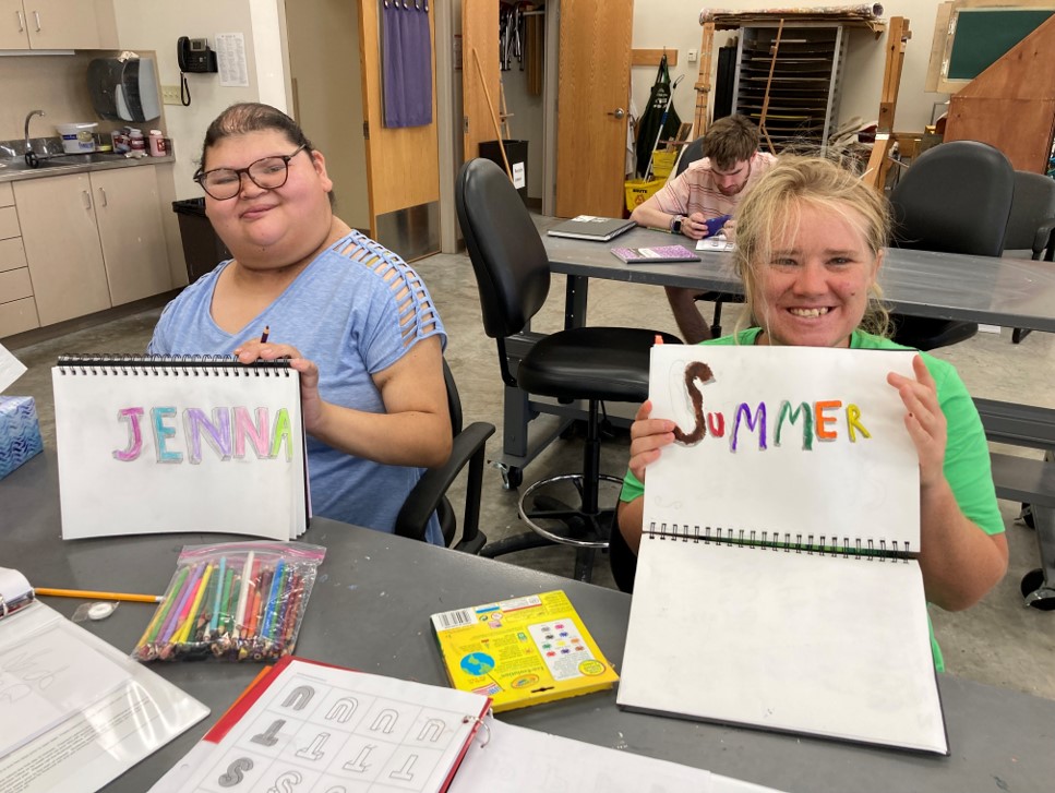 Two CFL students drawing their names, Jenna and Summer, in art class