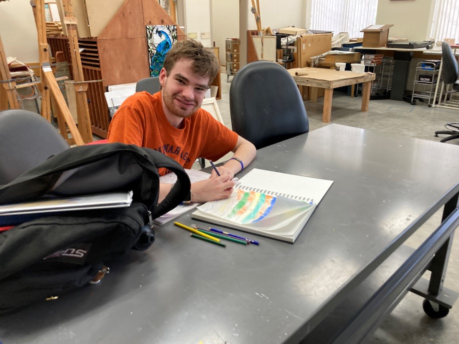 College for Life student proudly smiles at his artwork