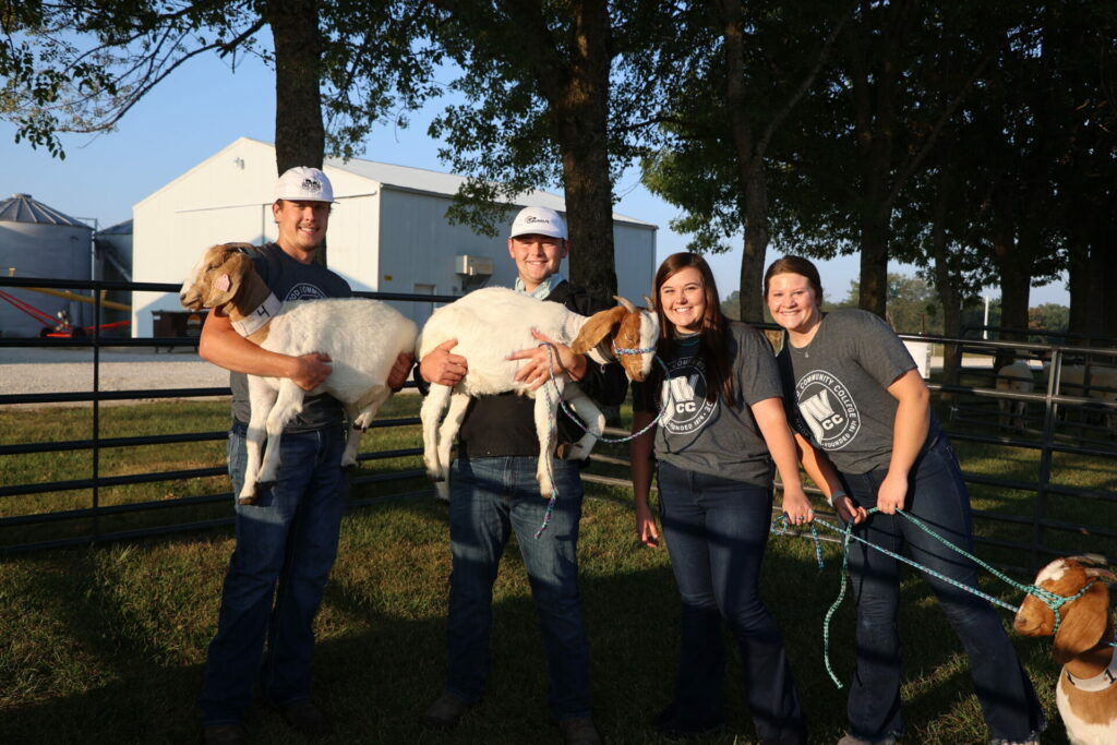 Several JWCC students smile with goats in arms